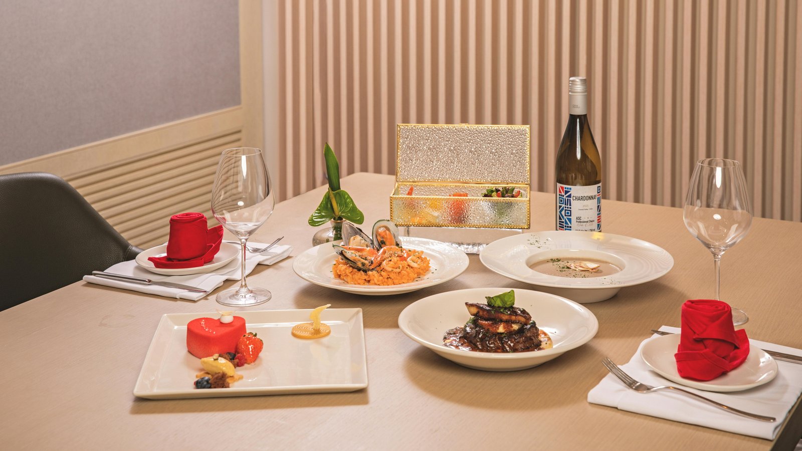 Elegant plated dinner service spread across a dining table with multiple courses and wine glasses.