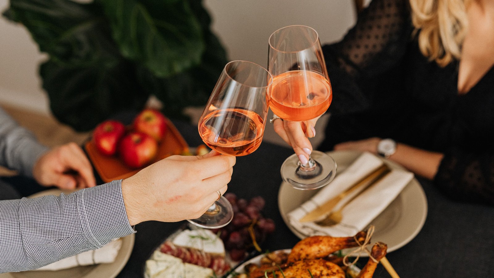 Couple toasting over an intimate plated dinner at their home dining table, candlelit and unhurried.