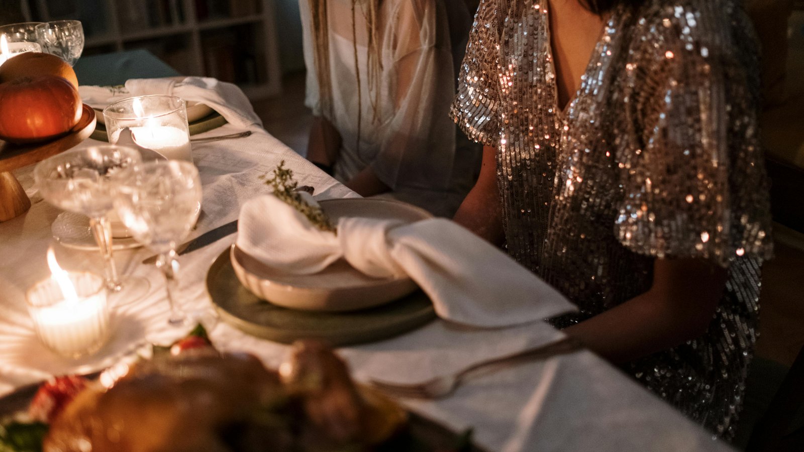 Elegant holiday table set with plated cuisine, host and guests laughing together in Denver home.
