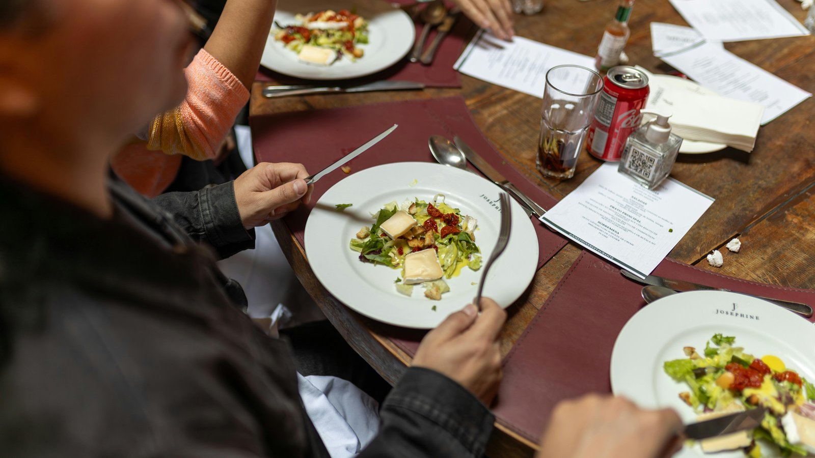 Satisfied dinner guests clinking glasses around an elegantly set dining table with plated cuisine.
