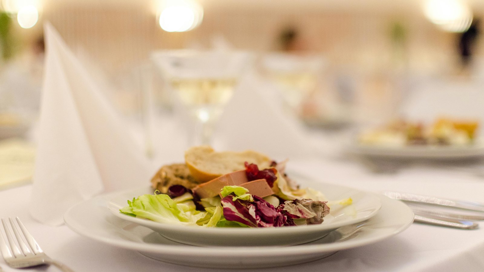 Elegant plated dinner with a transparent itemized bill overlay revealing hidden catering fees.