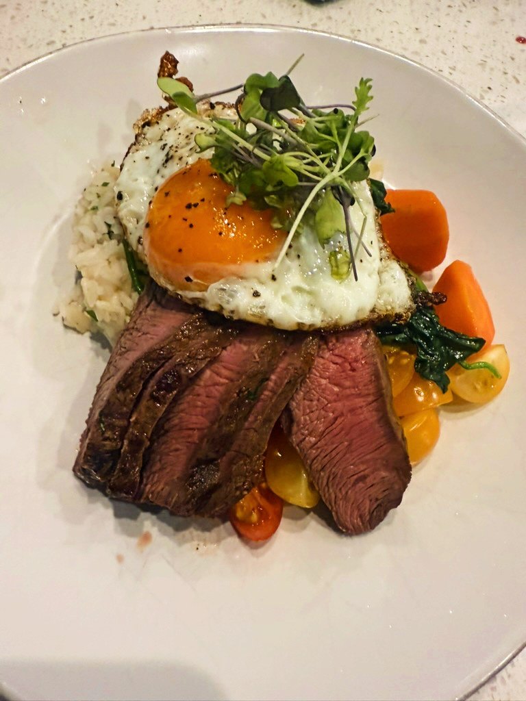 Sliced steak with a fried egg and roasted vegetables